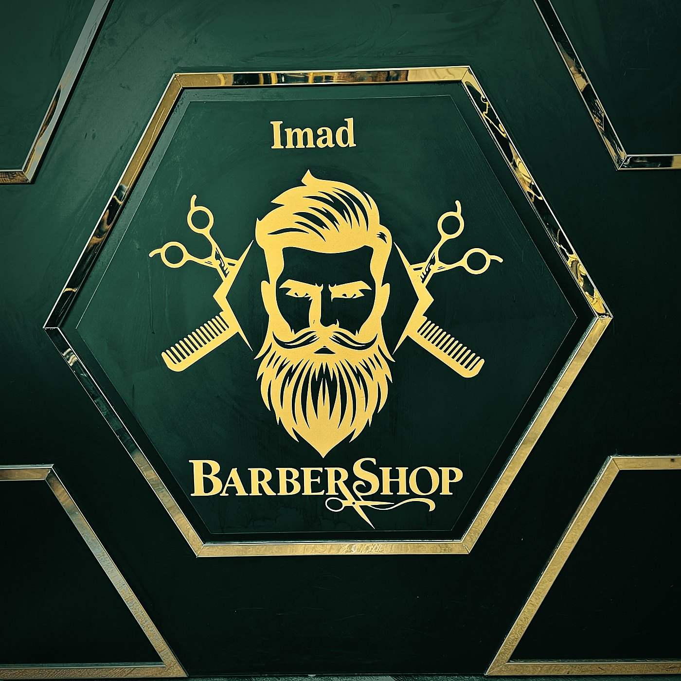 Logo des IMAD Barber Shop im goldenen Sechseck